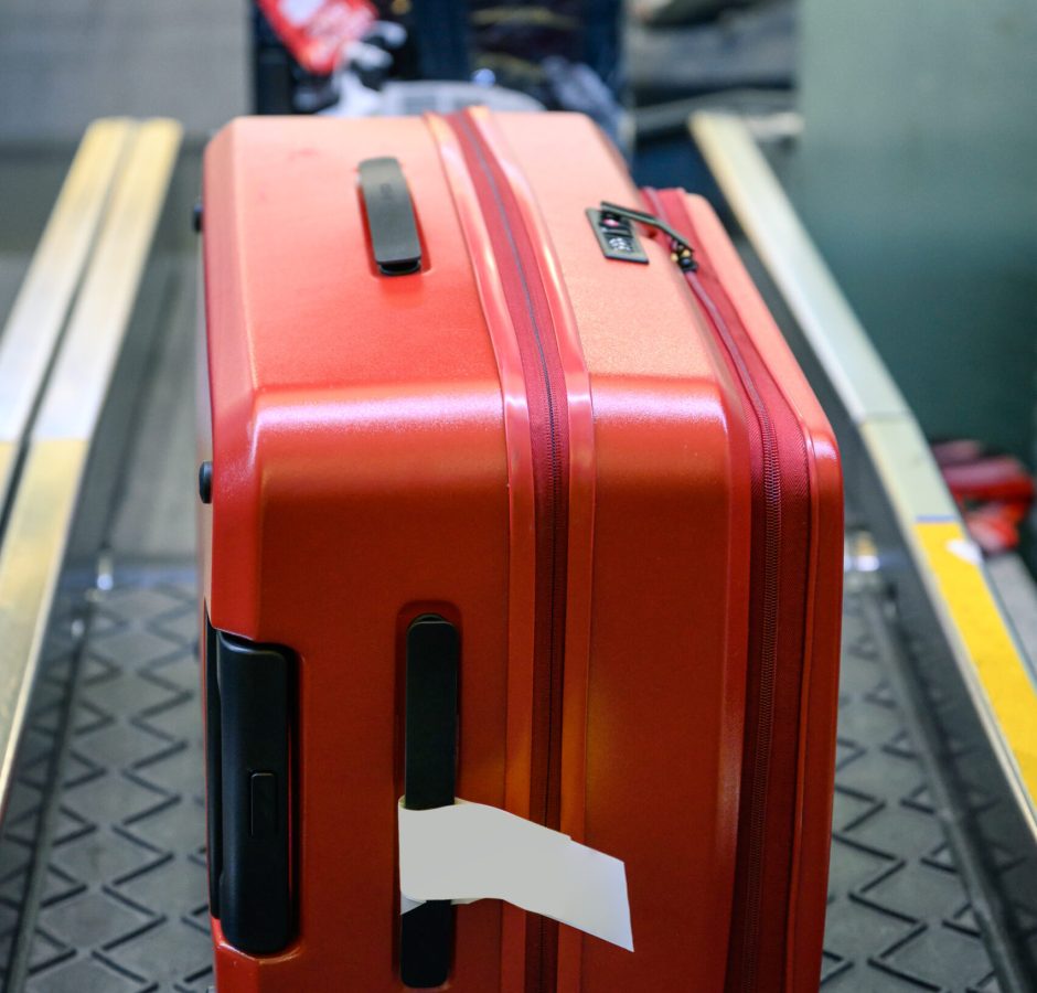 Red luggage on conveyor belt for check and scan on counter check-in at the airport