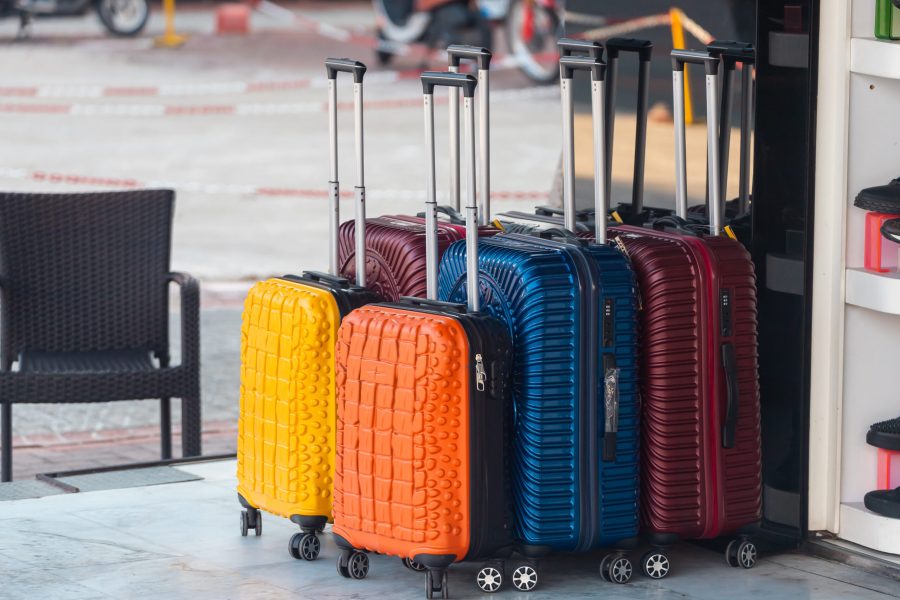 Bright blue, red, yellow and orange rows of suitcases with extended handles and different sizes are on sale in front of the store